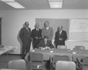 Fermilab founding director Robert Wilson signs the contract with the architectural and engineering company DUSAF in 1967.