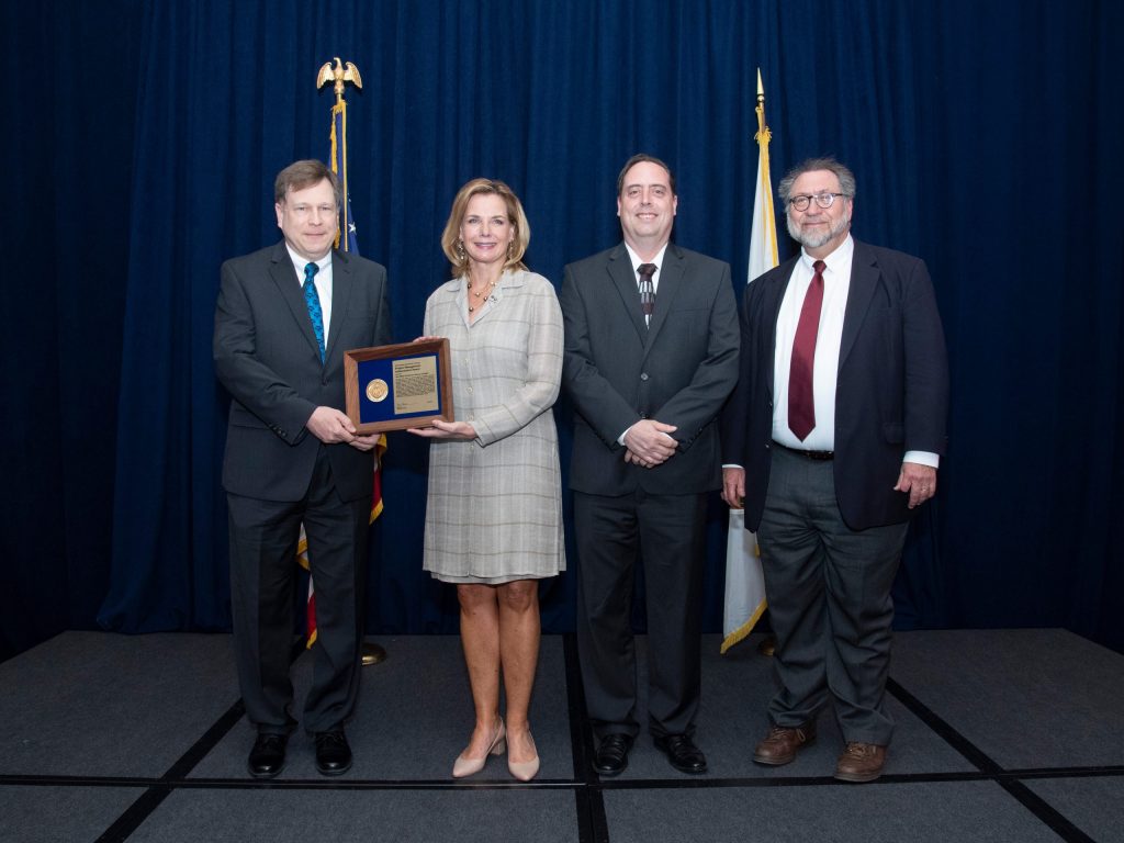 The Muon g-2 Project receives its DOE Achievement Award. From left: DOE Federal Project Director Paul Philp. National Nuclear Security Administration Undersecretary for Nuclear Security and Administrator Lisa Gordon‐Hagerty, Fermilab Muon g-2 Project Manager Chris Polly, DOE Federal Program Manager Ted Lavine. Photo: DOE