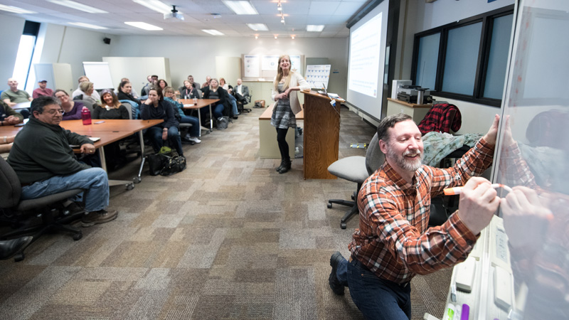 At a workshop, Fermilab's Erica Snider, at lectern, and Pete Cholewinski, at whiteboard, discuss how the laboratory community can be more LGBTQ+ inclusive. Photo: Reidar Hahn