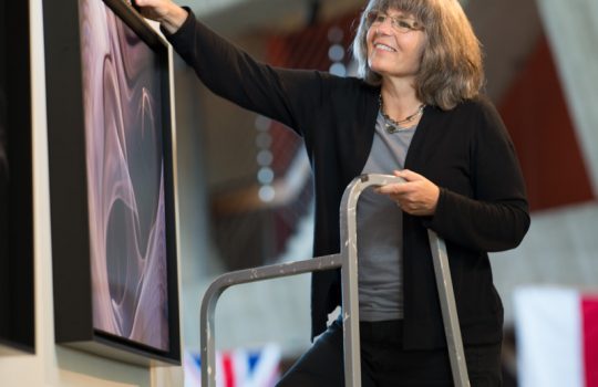 Georgia Schwender puts up a new exhibit in the Fermilab Art Gallery. Photo: Reidar Hahn