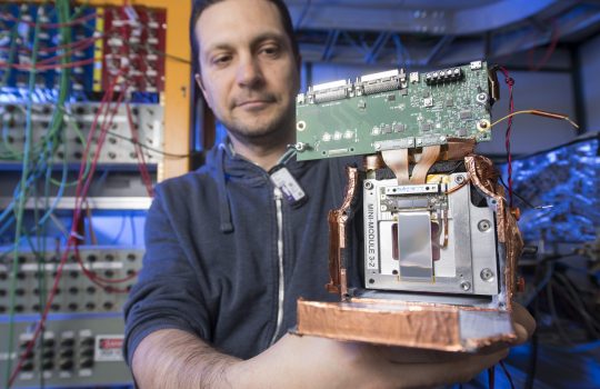 Fermilab engineer Lorenzo Uplegger holds a prototype of the final CMS tracking modules for testing. Photo: Reidar Hahn