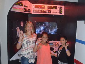 Three visitors say hello in the control room of the exhibit "Space Travels." Photo: SciTech Museum