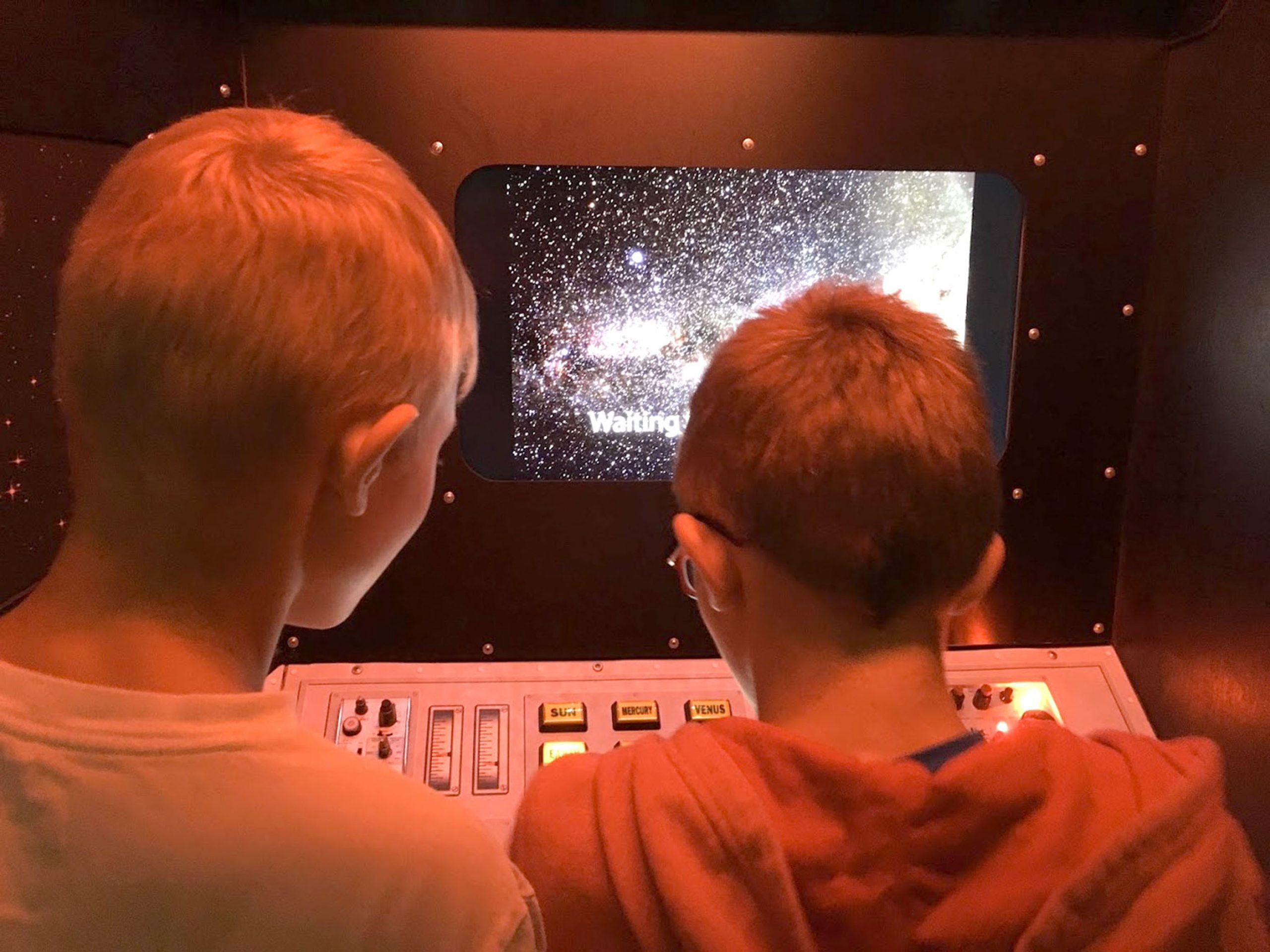 Two visitors view a space simulation in "Space Travels." Photo: SciTech Museum