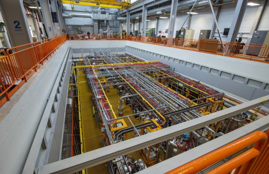 At an angle from the second floor looking down into a rectangle of multi-colored, interconnected pipes.