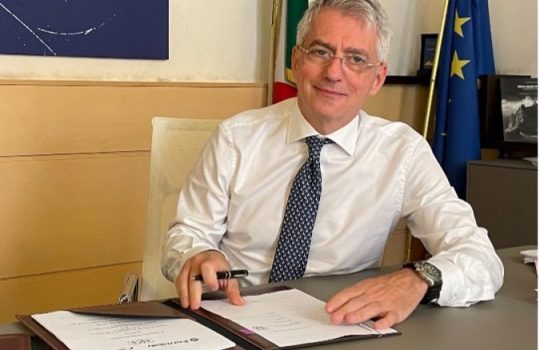 Man in white shirt sitting at desk, signing documents