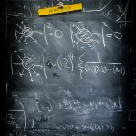 A chalkboard with equations scribbled over it, a magnetic clip holding a yellow piece of paper that reads Do Not Erase.