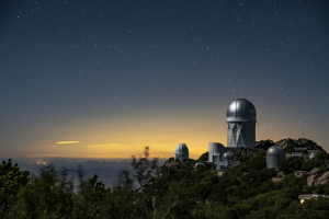 A telescope on a hill on a starry night