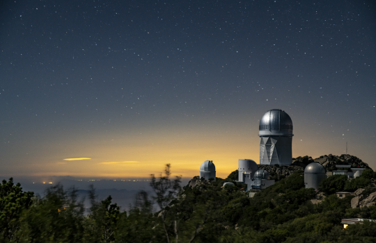 A telescope on a hill on a starry night