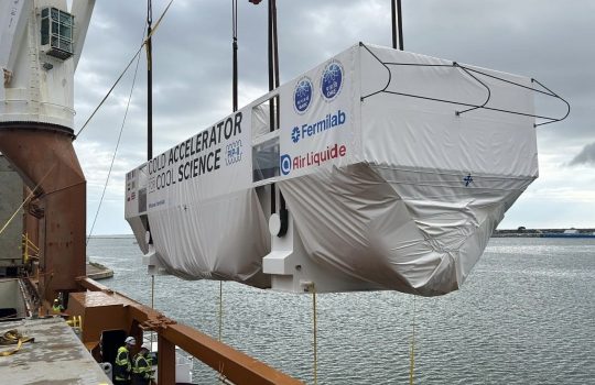 A large box is being transferred from a barge to a ship