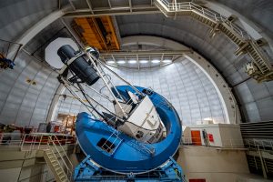 DESI’s instrument, a long black cylinder supported by the metal framework of the telescope, points at the domed ceiling