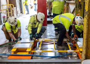 A crew installs beam clamps to connect the L-beam to the air cart. Photo: Matthew Kapust, SURF