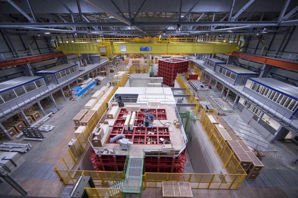 Two cube-shaped GTT cryostats (center, bottom and center, top), supported by red steel outer frames, contain DUNE prototype detectors at CERN. Shown here in 2017, they are each 1/20 the size of each DUNE detector module to be installed underground in South Dakota. Credit: Jim Shultz, Fermilab