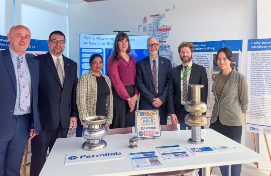 Group photo of participants at the UK showcase event, featuring 7 participants standing together in front of a table in a collaborative setting.