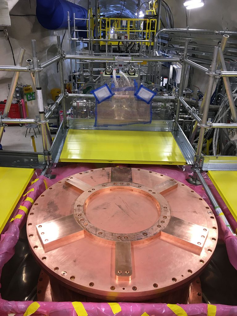 The large copper cryostat in the foreground, called the SNOBOX, houses SuperCDMS’s detectors. The yellow platforms surrounding it are temporary scaffolding for scientists to work inside the cryostat. Credit: Lauren Hsu