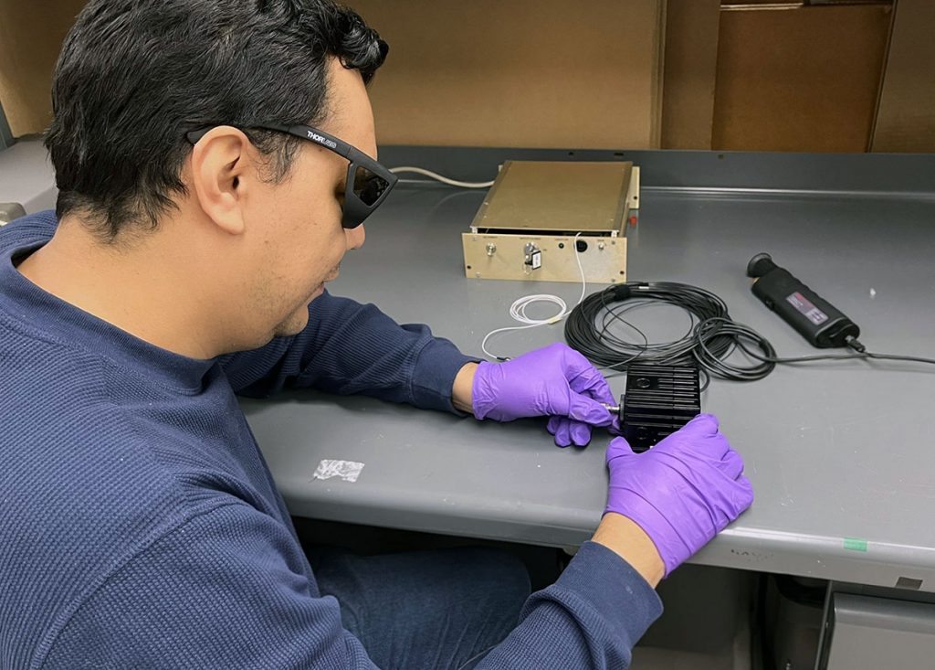 Jairo Rodriguez works with a fiber cable, a laser box and a sensor at South Dakota School of Mines and Technology. Credit: Diana Leon