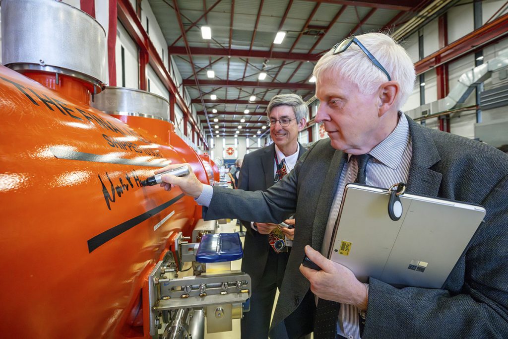 SLAC director John Sarrao, left, and Fermilab director Norbert Holtkamp sign their names on the final Fermilab cryomodule. Its completion marks a milestone for the high-energy LCLS upgrade. Credit: JJ Starr, Fermilab