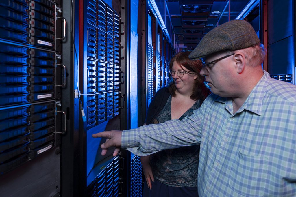 Scarlet Norberg and Steven Timm stand in front of disk drive storage in the computing center at Fermilab.